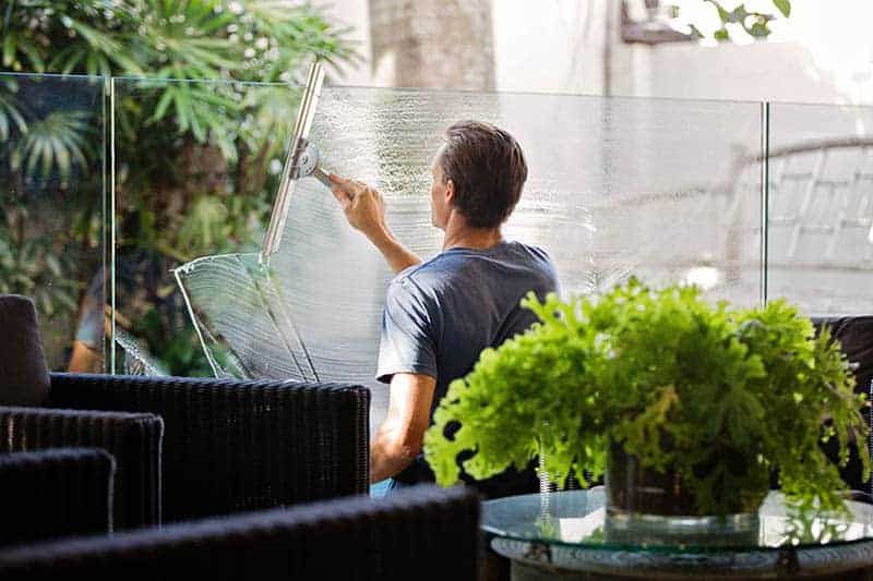 Mann putzt Fenster im Café