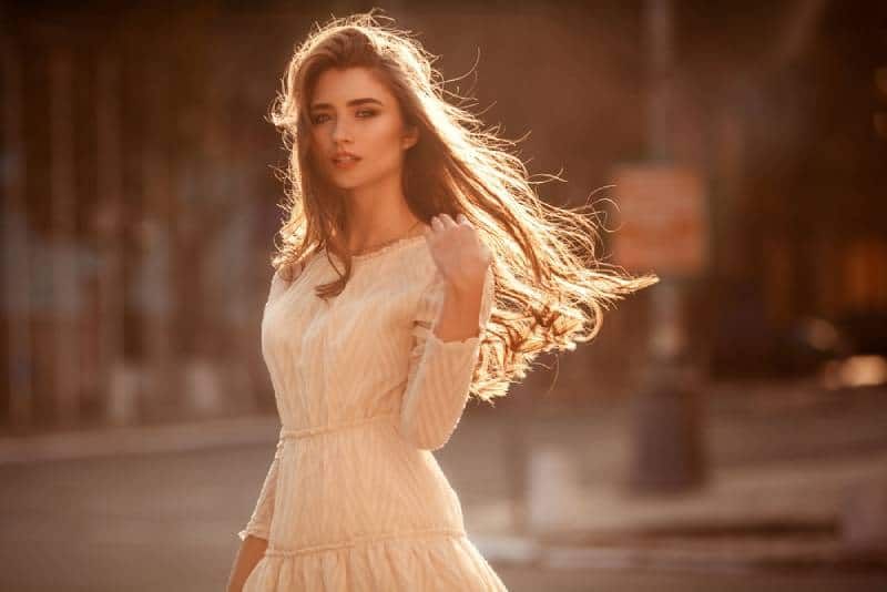 Schöne junge Dame mit langen Haaren und süßem Kleid auf der Straße