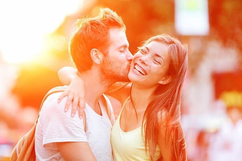 Paar küsst Glücksspaß. Interracial junges Paar umarmt sich lachend beim Date. Kaukasischer Mann, asiatische Frau in Manhattan, New York City, USA.