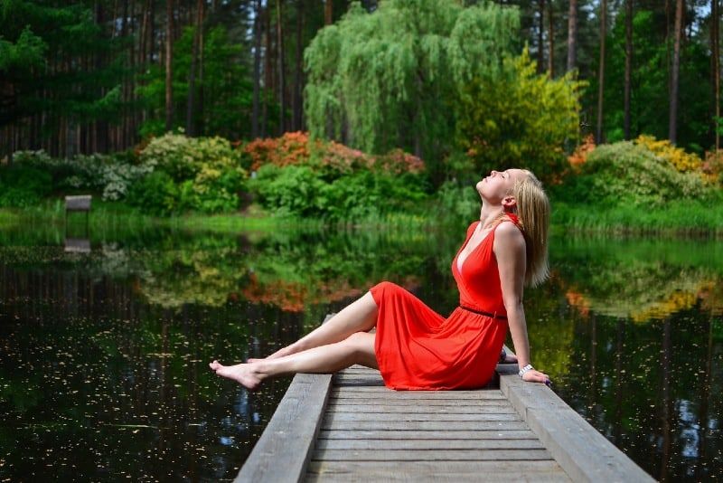 Frau im roten Kleid sitzt auf Holzsteg