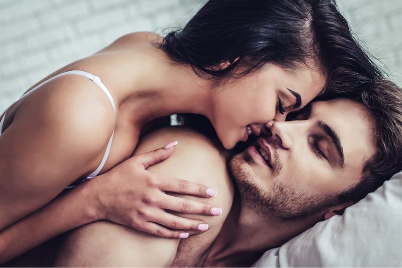 schöne junge Frau küsst Mann im Bett