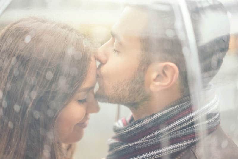 Mann küsst süße Frau auf die Stirn