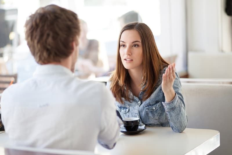Wütende Frau redet mit Mann, während sie am Tisch sitzt