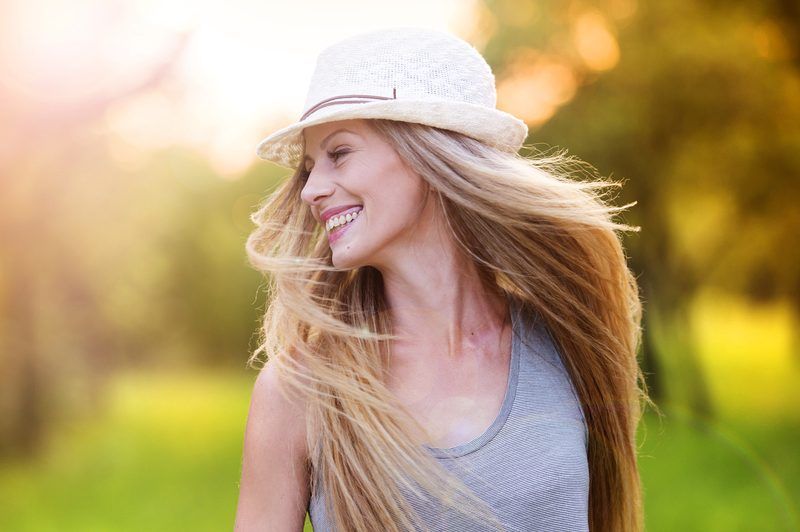 Eine Frau mit langen blonden Haaren und einem Hut auf dem Kopf lacht