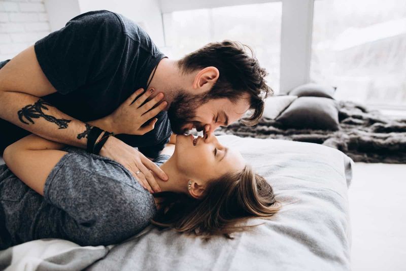 Mann und Frau wollen sich küssen, während sie auf dem Bett liegen