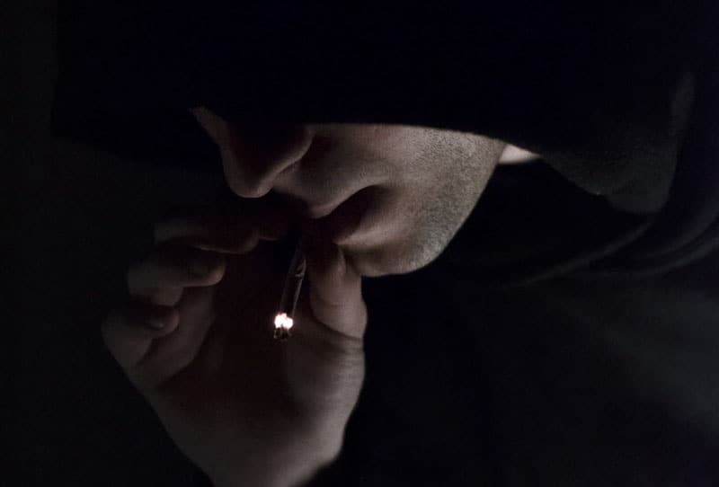 Mann im Hoodie raucht Zigarette