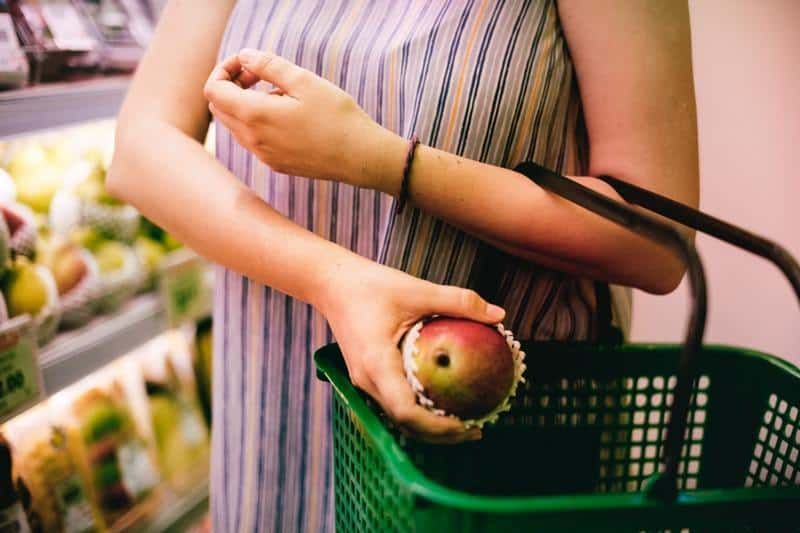 Frau kauft einen Apfel im Supermarkt
