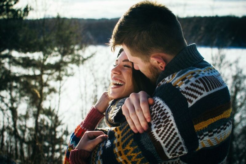 Junger Mann im Pullover umarmt ein Mädchen