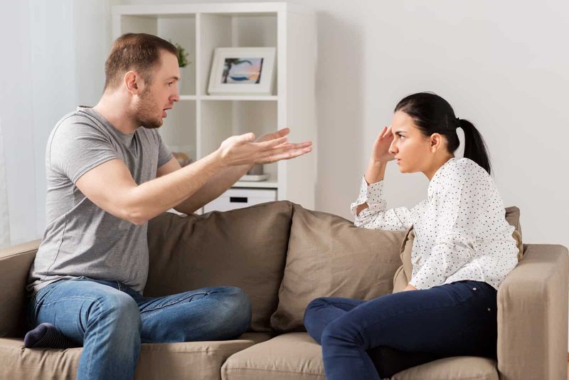 Ein Mann und eine Frau sitzen auf der Couch und streiten