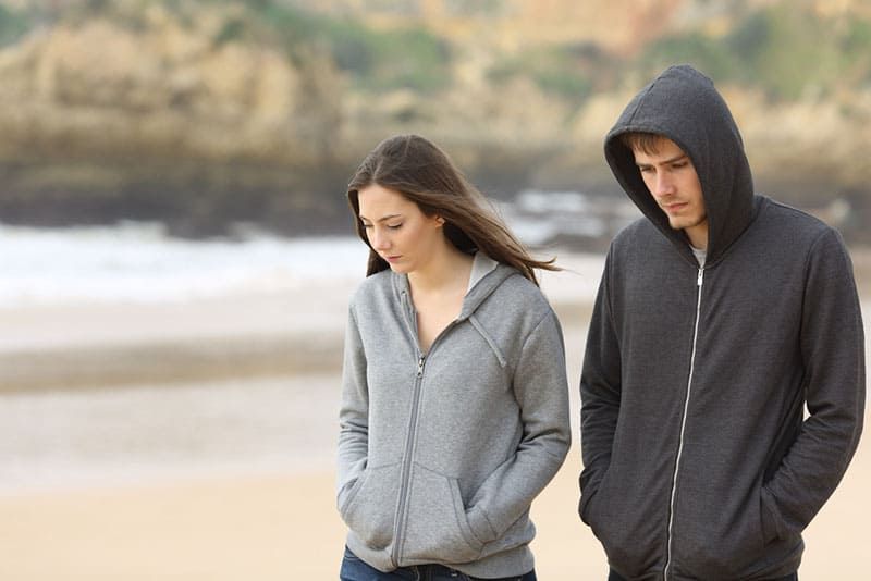 trauriges Paar, das am Strand spazieren geht