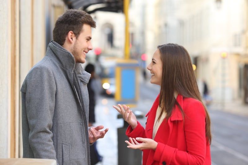 lächelnder Mann und Frau, die sich unterhalten, während sie im Freien stehen