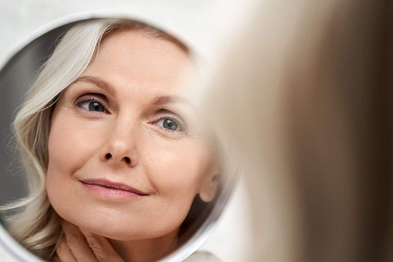 Glückliches 50er-Jahre-Frauenmodell mittleren Alters, das die Gesichtshaut berührt