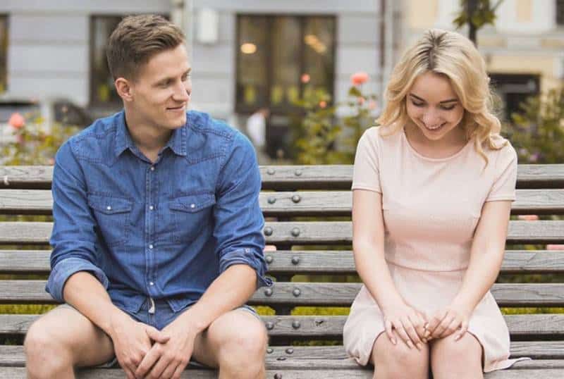 Lächelnder Mann und Frau sitzen auf einer Parkbank