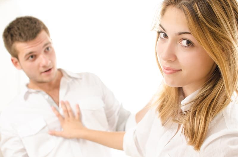 Eine Frau schubst einen Mann mit der Hand, während er versucht, mit ihr zu flirten