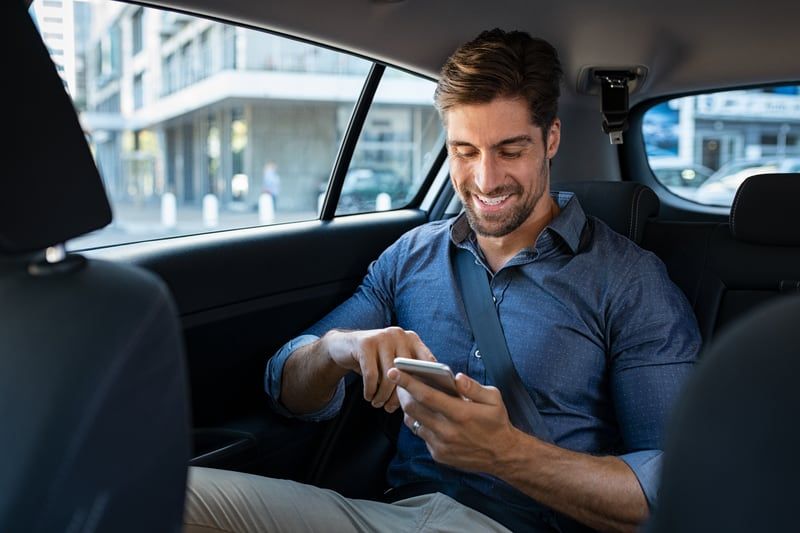 Mann schreibt SMS, während er im Taxi sitzt