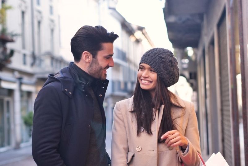 Mann in schwarzer Jacke und Frau machen Blickkontakt, während sie im Freien stehen