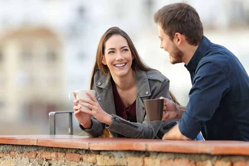 glückliches Paar, das draußen spricht und Kaffee trinkt