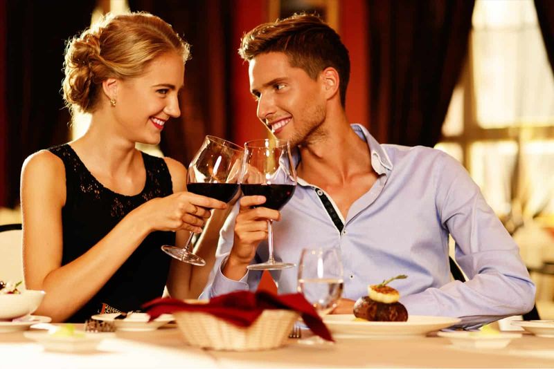 Ein Mann und eine Frau stoßen mit Wein an und schauen sich dabei an