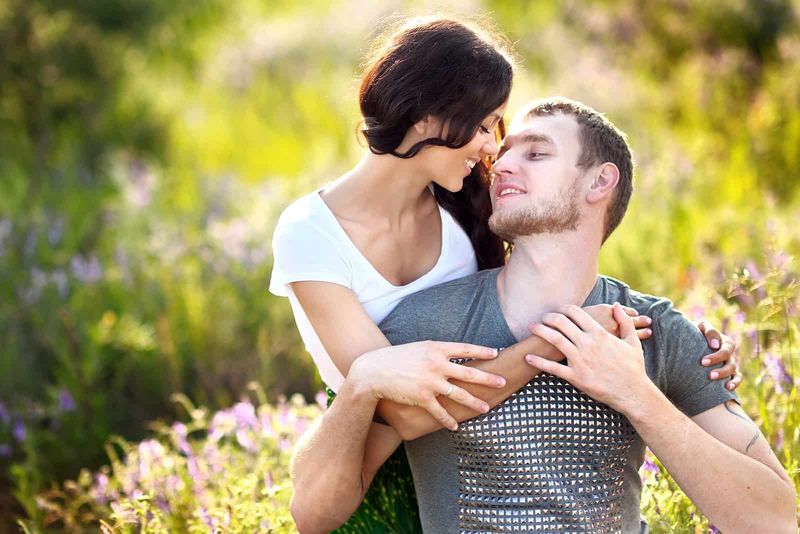 Eine Frau kuschelt mit einem Mann in einer Blumenwiese