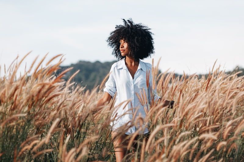 eine attraktive afroamerikanische Frau, die in einem Weizenfeld steht