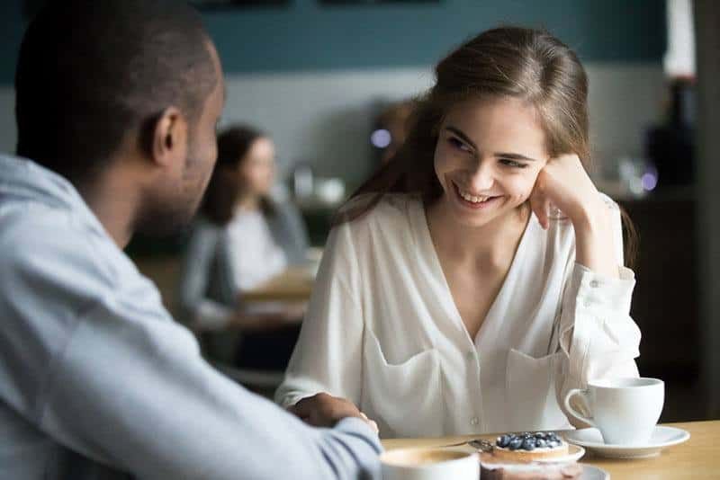 Schüchterne Frau lächelt mit Mann im Café