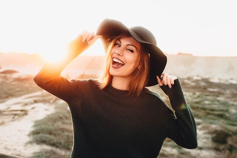 eine lächelnde Frau mit einem schwarzen Hut auf dem Kopf