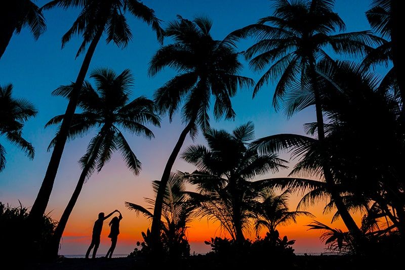 Silhouette von Mann und Frau neben Bäumen bei Sonnenuntergang