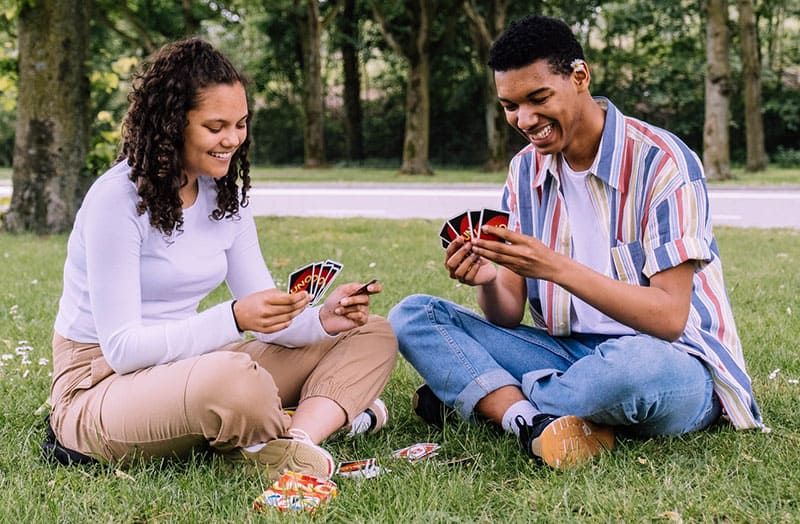 Mann und Frau spielen Karten und sitzen im grünen Gras