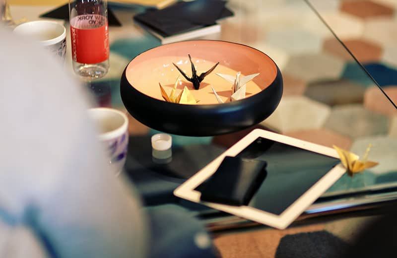 Origami in Gefäßform in einer Schüssel mit Lasche platziert, beide auf dem Tisch