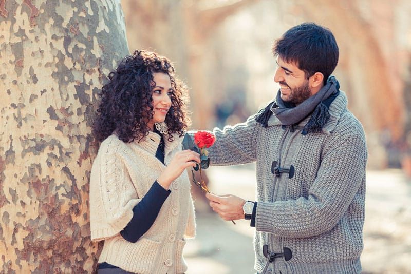 Glücklicher Mann, der einer Frau eine Blume schenkt