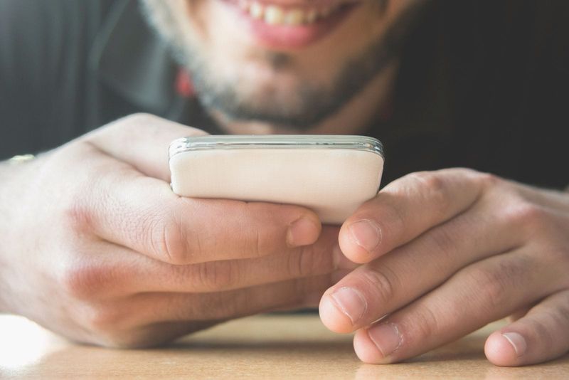 Zugeschnittenes Bild eines Mannes, der eine SMS an das Telefon und die Hände sendet