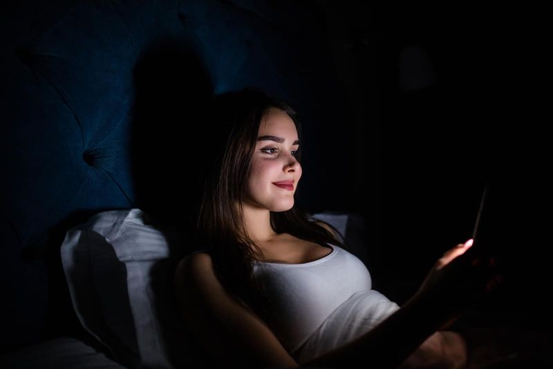Frau liegt im Dunkeln und schreibt SMS