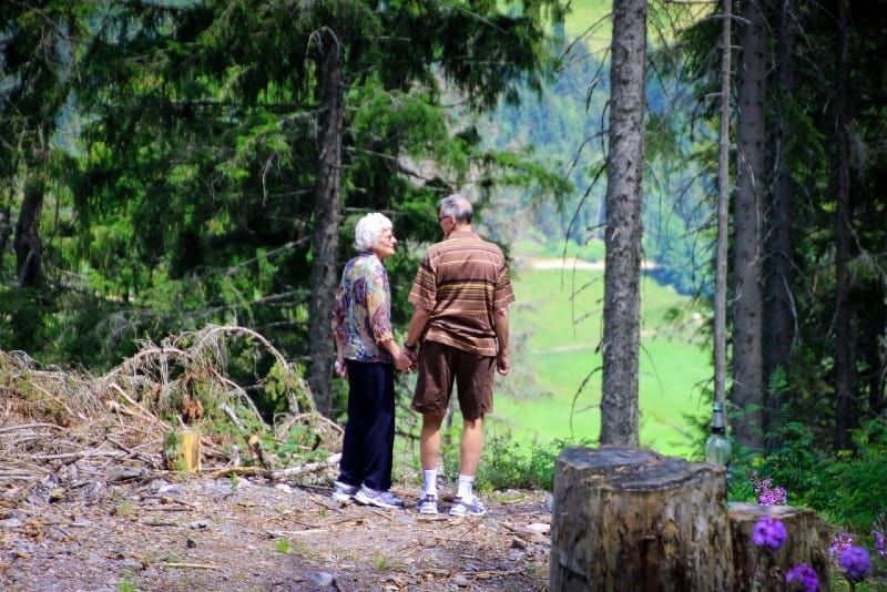 Mann und Frau halten Händchen, während sie im Wald stehen