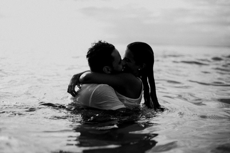 Mann und Frau küssen sich, während sie im Wasser stehen