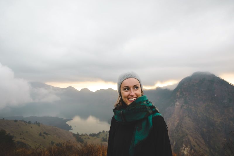 Frau mit grünem Schal lächelt, während sie in der Nähe des Berges steht