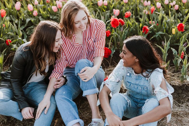 Drei Frauen sitzen lächelnd in der Nähe eines Tulpenfeldes