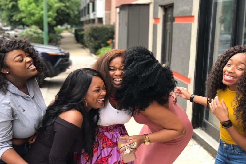 Fünf Frauen lachen, während sie draußen stehen