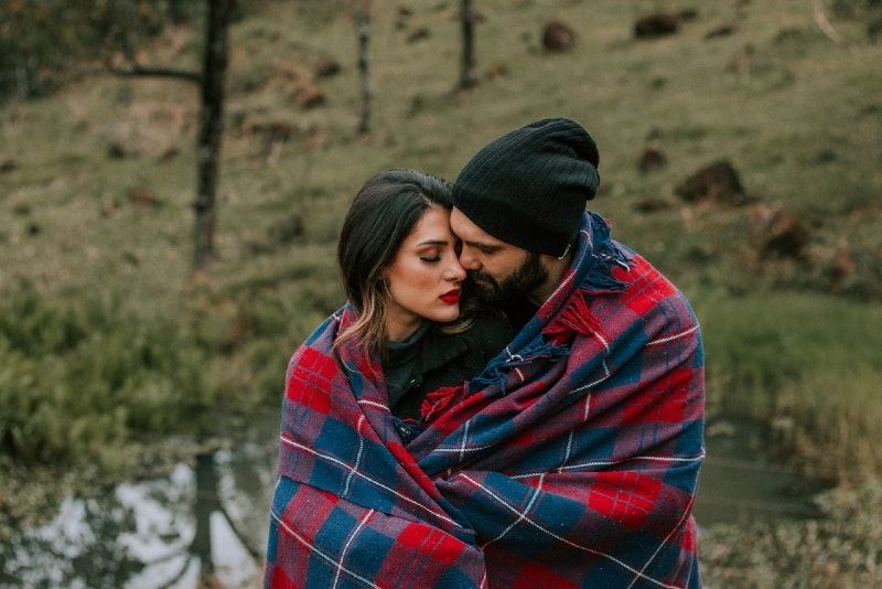 Mann und Frau umarmen sich in roter und schwarzer Decke