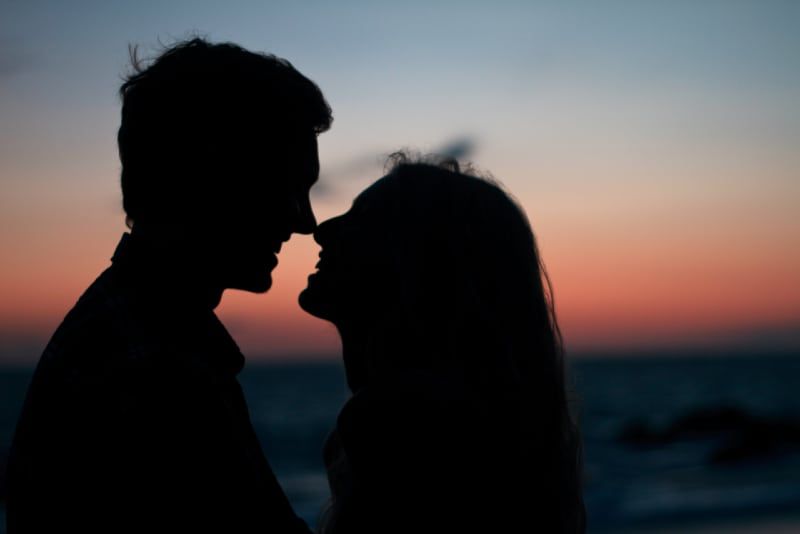 Mann und Frau machen Blickkontakt am Strand bei Sonnenuntergang