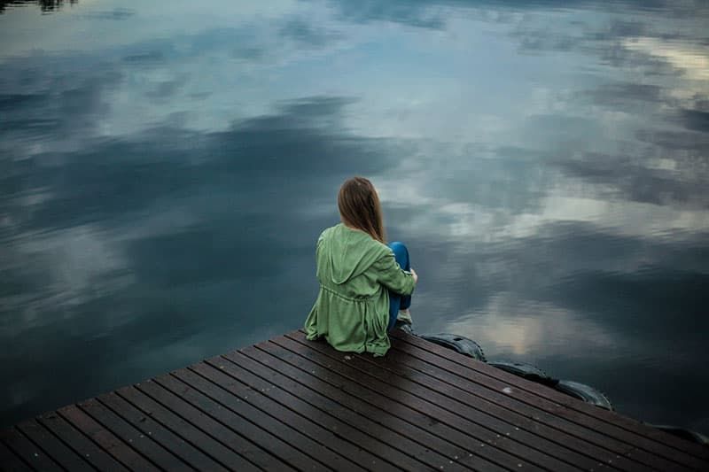 Traurige Frau sitzt am See