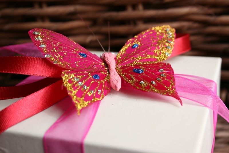 Geburtstagsgeschenk mit Schmetterlingsband, glitzernd in verschiedenen Farben