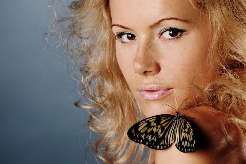 Blonde Frau mit Schmetterling auf ihrer Schulter