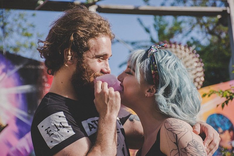 Mann und Frau mit blauen Haaren lächeln und essen Zuckerwatte