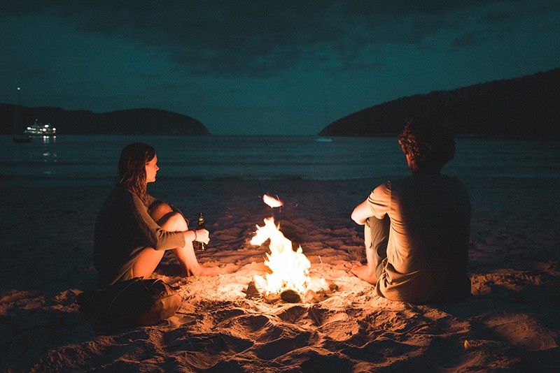 Mann und Frau mit Knochenfeuer sitzen am Meeresufer