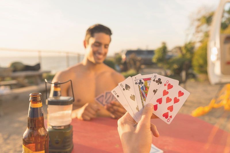 Hemdloser Mann spielt Karten im Freien mit seiner Freundin in beschnittenem Bild