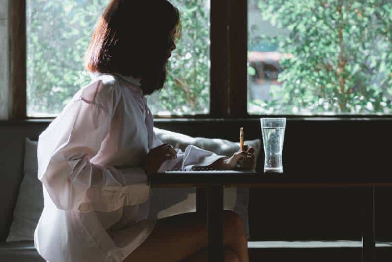 Porträt einer Frau, die am Tisch einen Brief schreibt