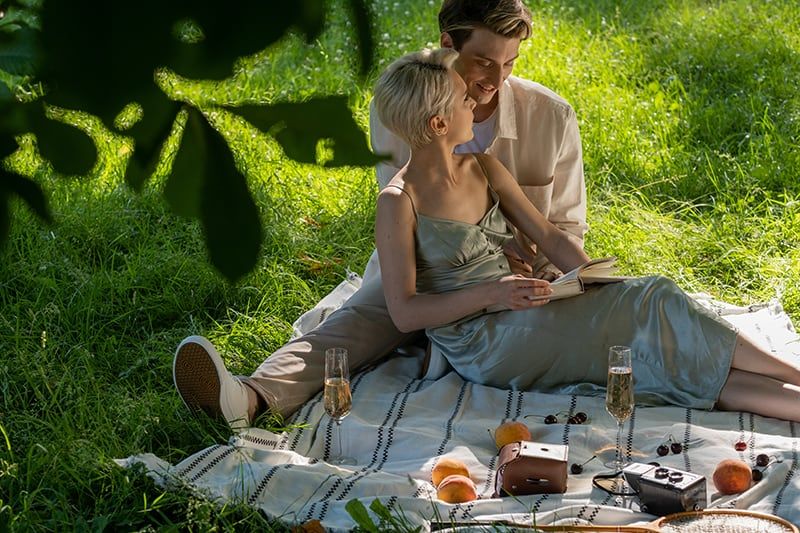 frau liest ihrem freund bei einem romantischen picknick liebesgedichte vor