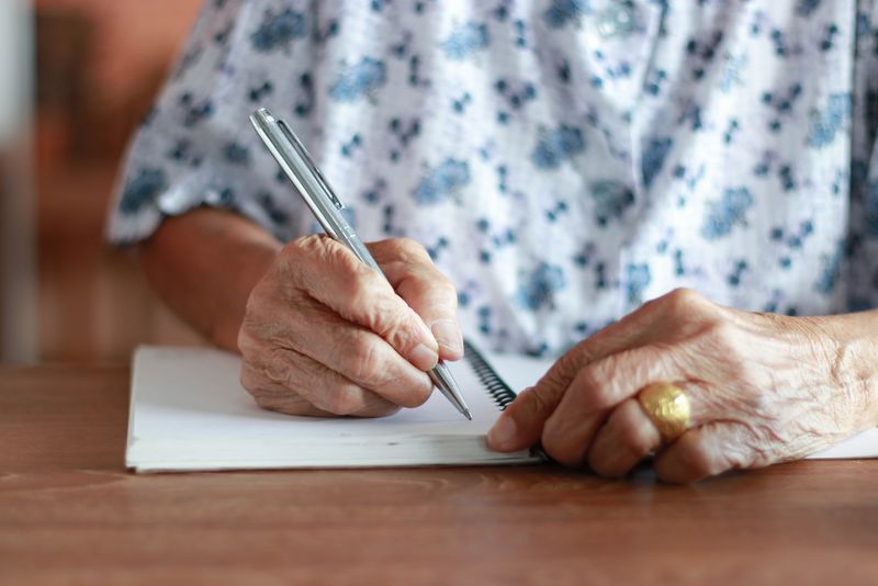 Eine Frau sitzt an einem Tisch und schreibt einen Brief