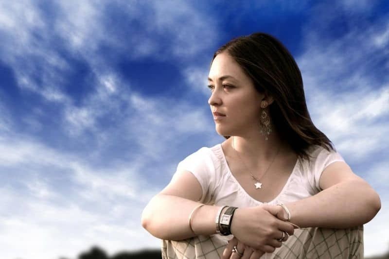 Nachdenkliche Frau sitzt mit blauem Himmel als Hintergrund