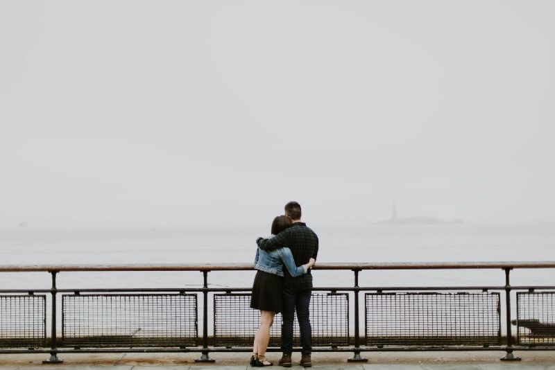 Mann und Frau umarmen sich, während sie in der Nähe des Zauns stehen